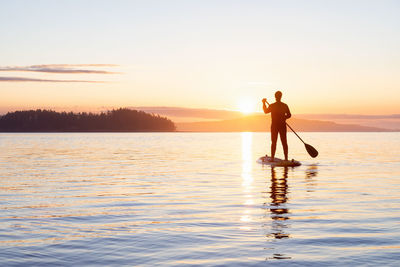 Silhouette man standing in water against sky