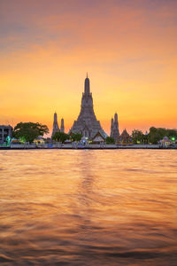 Temple by building against sky during sunset