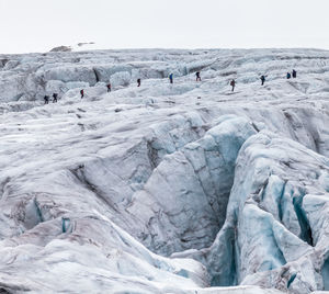 Mid distant view of hikers walking on glacier