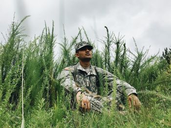 Young man standing on hill against cloudy sky