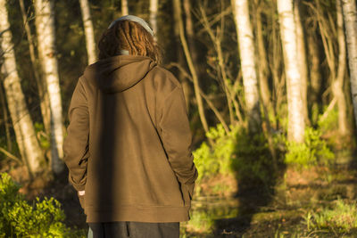 Rear view of woman walking against trees at forest