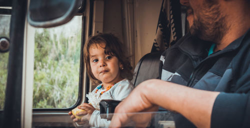 Close-up of father and daughter sitting in land vehicle