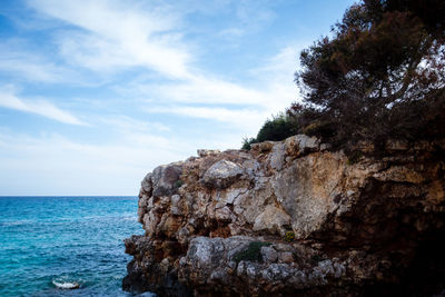 Rock formation by sea against sky