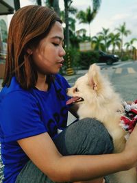 Young woman with puppy sitting on road