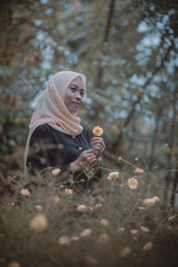 Woman holding flower on field