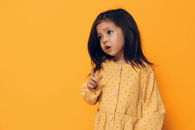 Young woman standing against yellow background