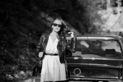 Portrait of young woman standing in car