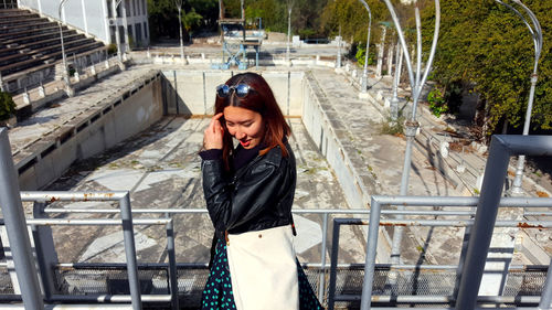 Young woman looking at camera while standing on railing