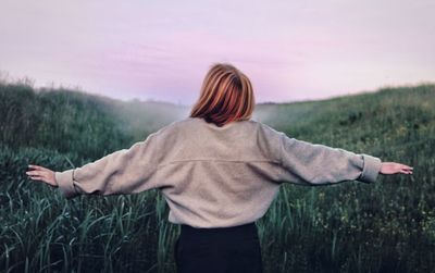 Rear view of woman standing on field against sky