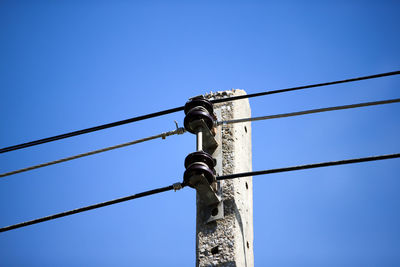 Low angle view of telephone pole against clear blue sky