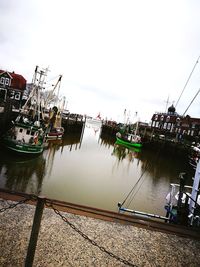 Boats moored at harbor against sky