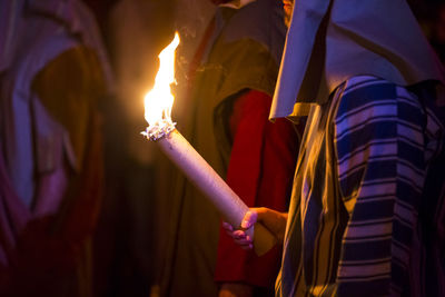 Close-up of hand holding lit candles