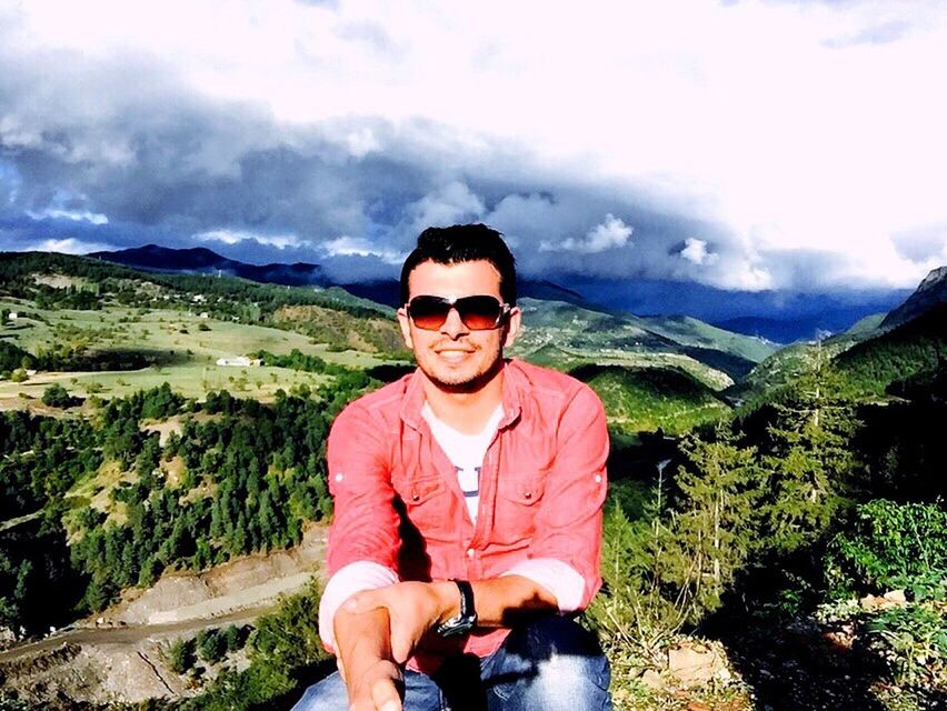 lifestyles, mountain, casual clothing, leisure activity, looking at camera, portrait, young adult, sky, person, smiling, front view, standing, cloud - sky, landscape, young men, mountain range, three quarter length, sunglasses