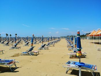 Chairs on beach against clear blue sky