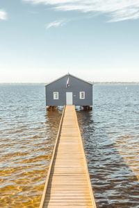 Pier over sea and houses against sky