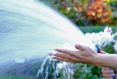 Close-up of hand against waterfall