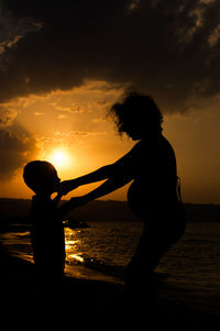 Silhouette mother and son standing on beach