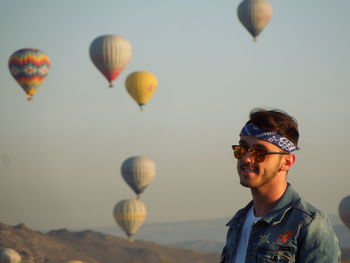 Portrait of young  man in hot air balloons flying against sky in cappadocia