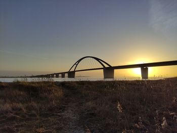 View of bridge on field against sky at sunset