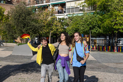 Young diverse friends walking on the street with the lgbt rainbow flag.