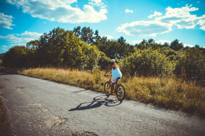 Man riding bicycle on road against sky