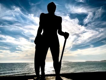 Silhouette man standing at beach against sky