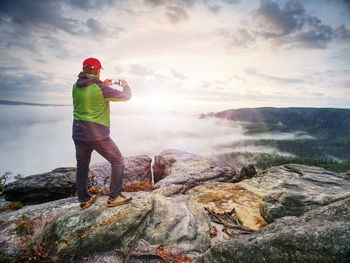 Traveler taking vacation photos of beautiful sunset in autumn nature by smartphone, holiday