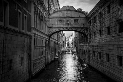 Arch bridge over canal amidst buildings in city