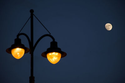 Low angle view of illuminated street light against sky