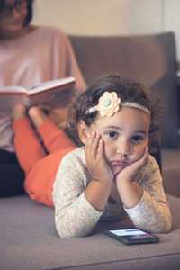 Portrait of girl with mother relaxing on bed at home