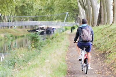 Rear view of man riding bicycle on road