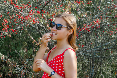 Midsection of woman wearing sunglasses against plants