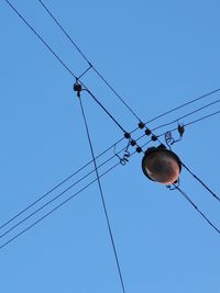 Low angle view of power cables against clear blue sky