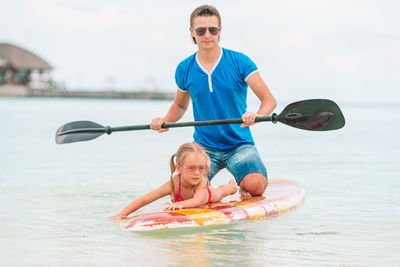 Portrait of father and man on paddleboard in sea