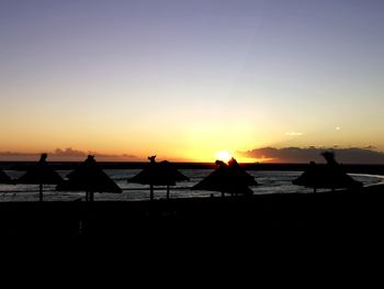 Silhouette people on beach against sky during sunset