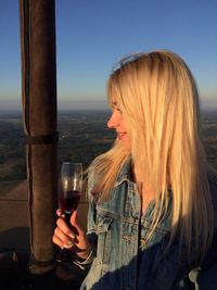 Beautiful woman with blond hair looking away while holding wineglass