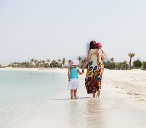 Rear view of women at beach against clear sky