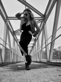 Full length of young woman standing on bridge
