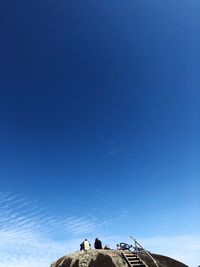 Rear view of people sitting against blue sky