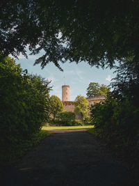 Road amidst trees and buildings against sky