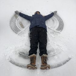 High angle view of woman making angel on snow