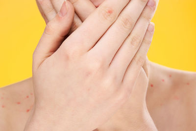 Close-up of hands against yellow background