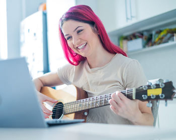 Portrait of young woman playing guitar