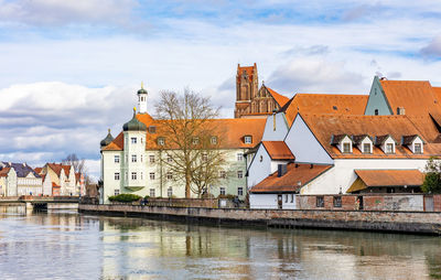 Buildings by river against sky