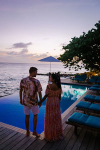 Rear view of couple standing by sea against sky