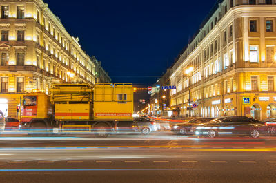 Light trails on city street by buildings at night