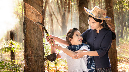 Woman collecting a latex from a rubber tree