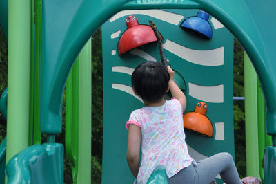 Rear view of girl sitting against blue wall