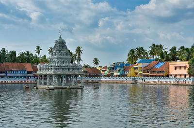 View of building by lake against cloudy sky