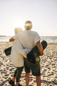 Elderly senior couple standing with arms around while standing at beach